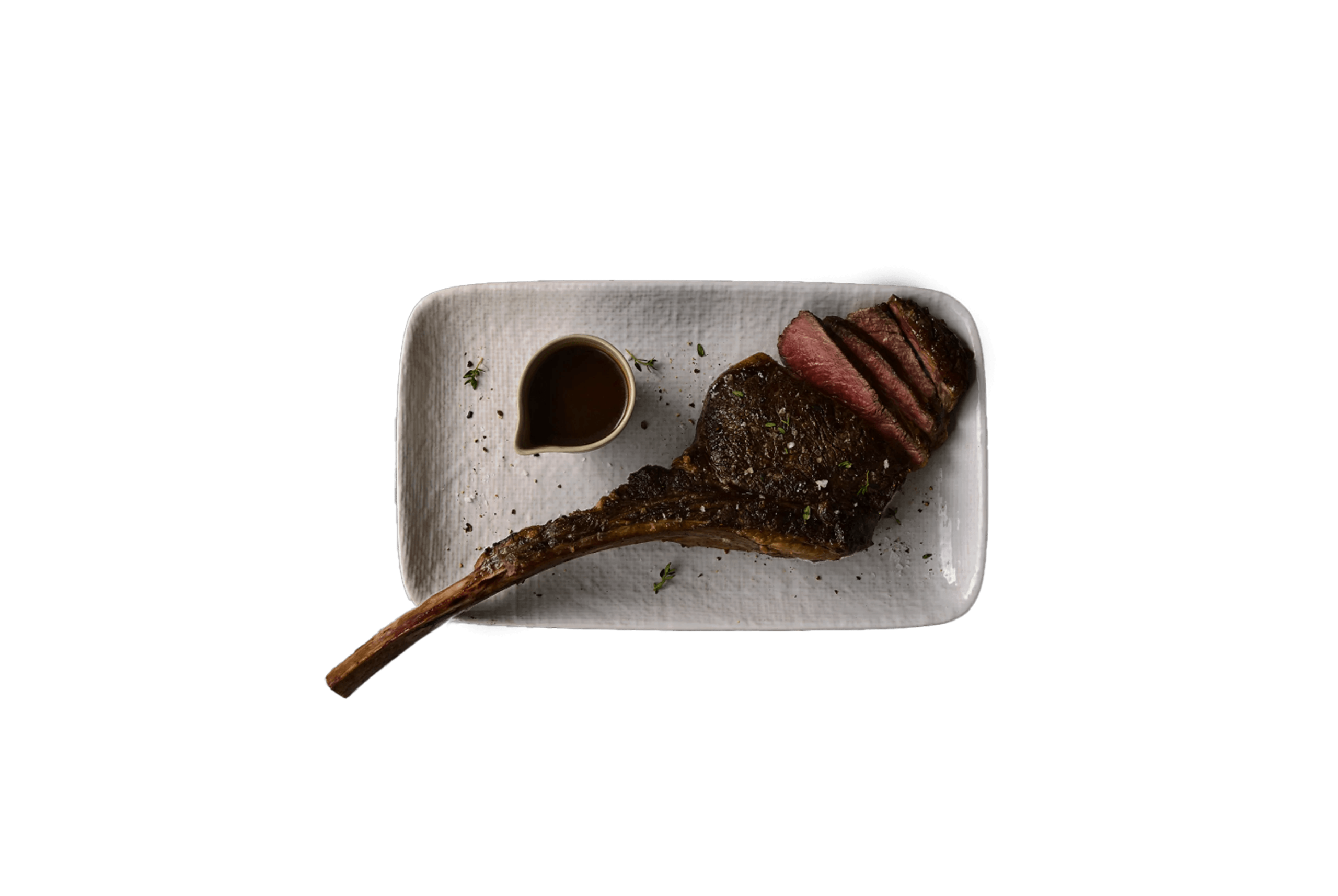 Tomahawk steak, sliced and plated with sauce on a white dish.