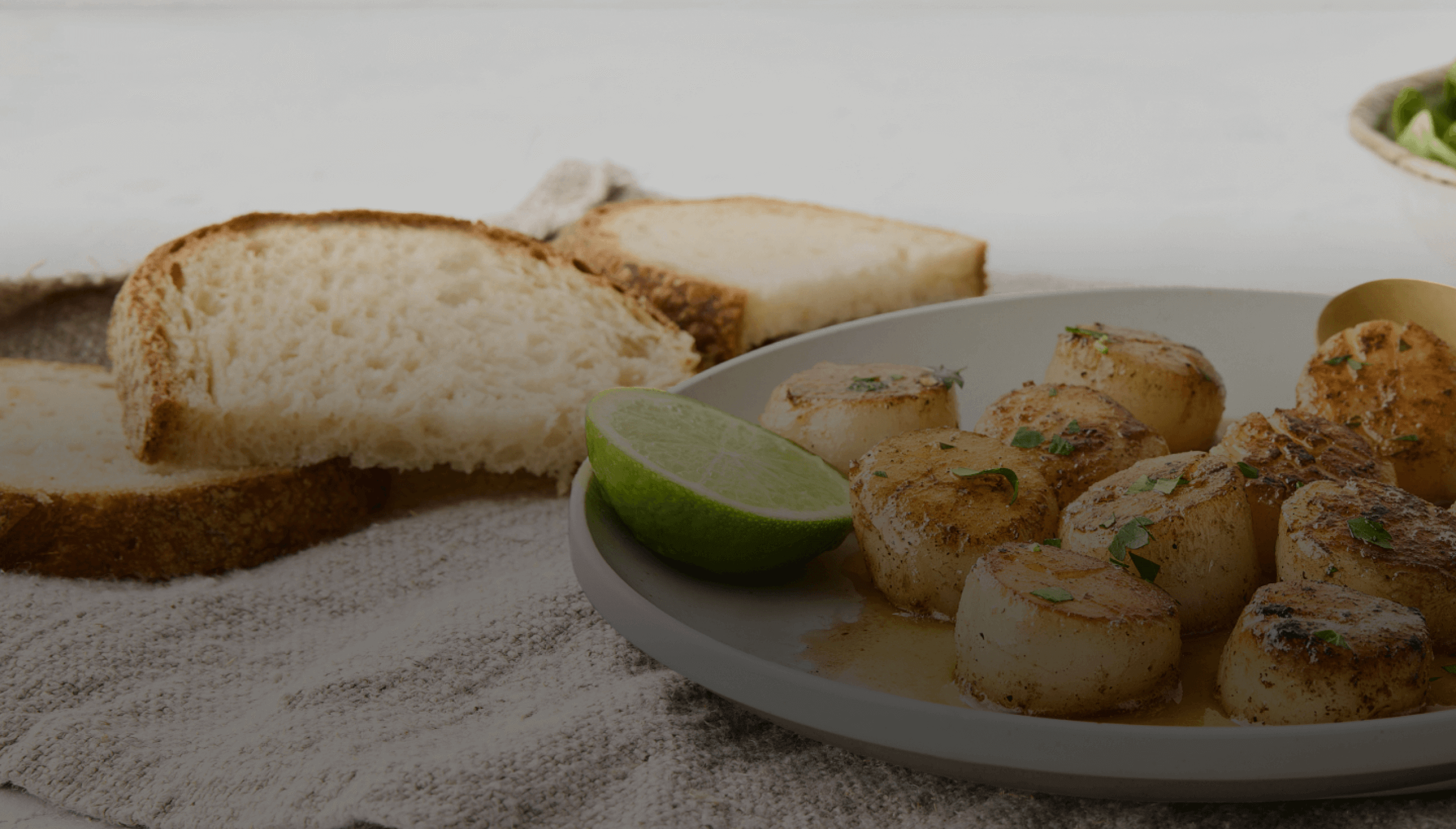 Seared scallops with lime and bread on a plate