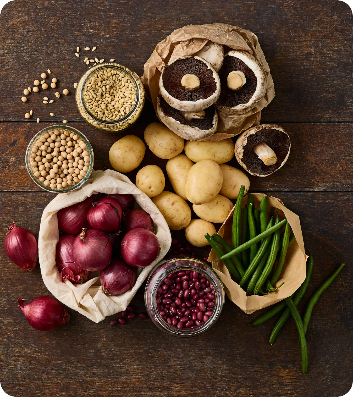 Assortment of fresh, plant-based ingredients: red onions, potatoes, mushrooms, beans, lentils, and green beans.