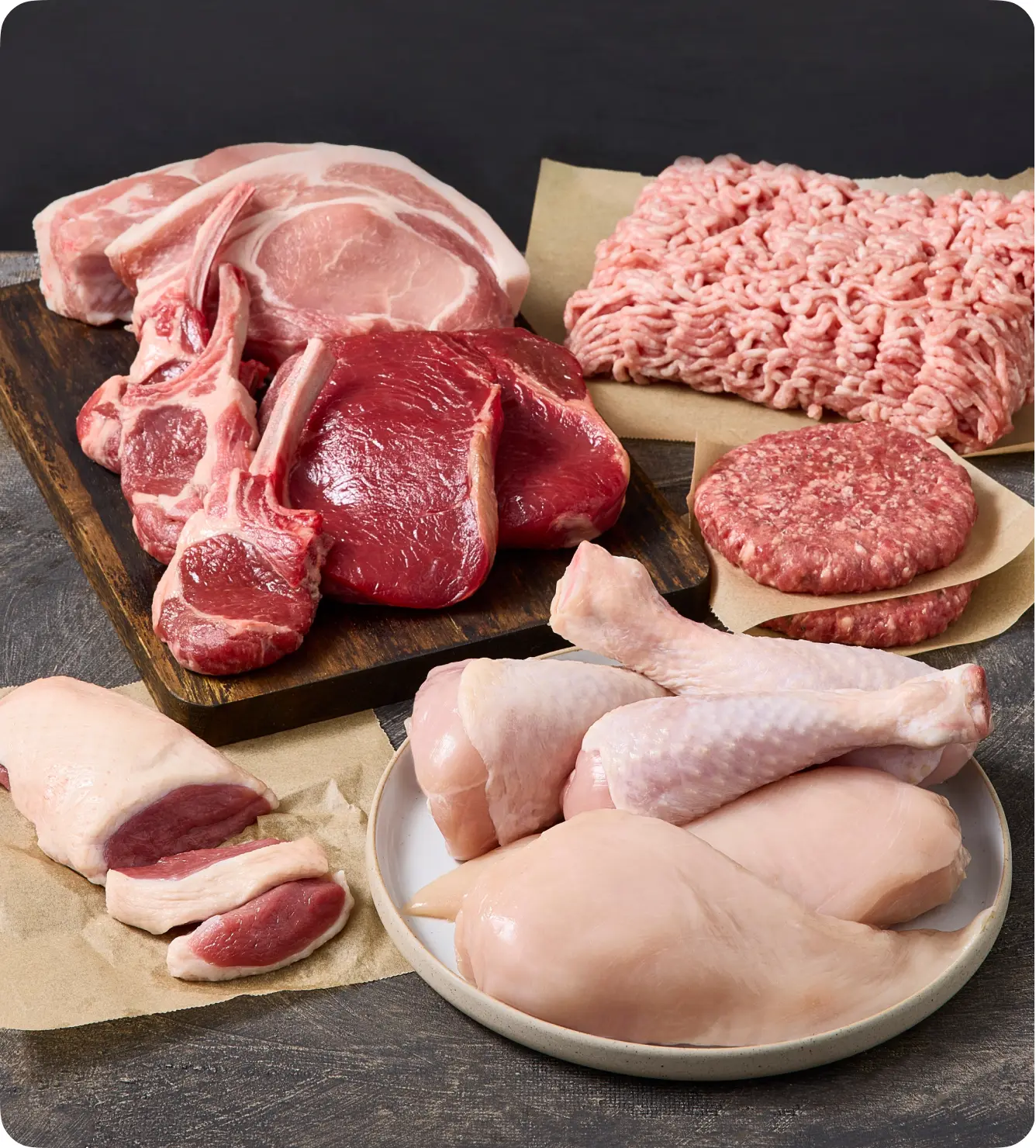 Variety of raw meats: pork chops, ground beef, lamb chops, chicken breasts, and duck.