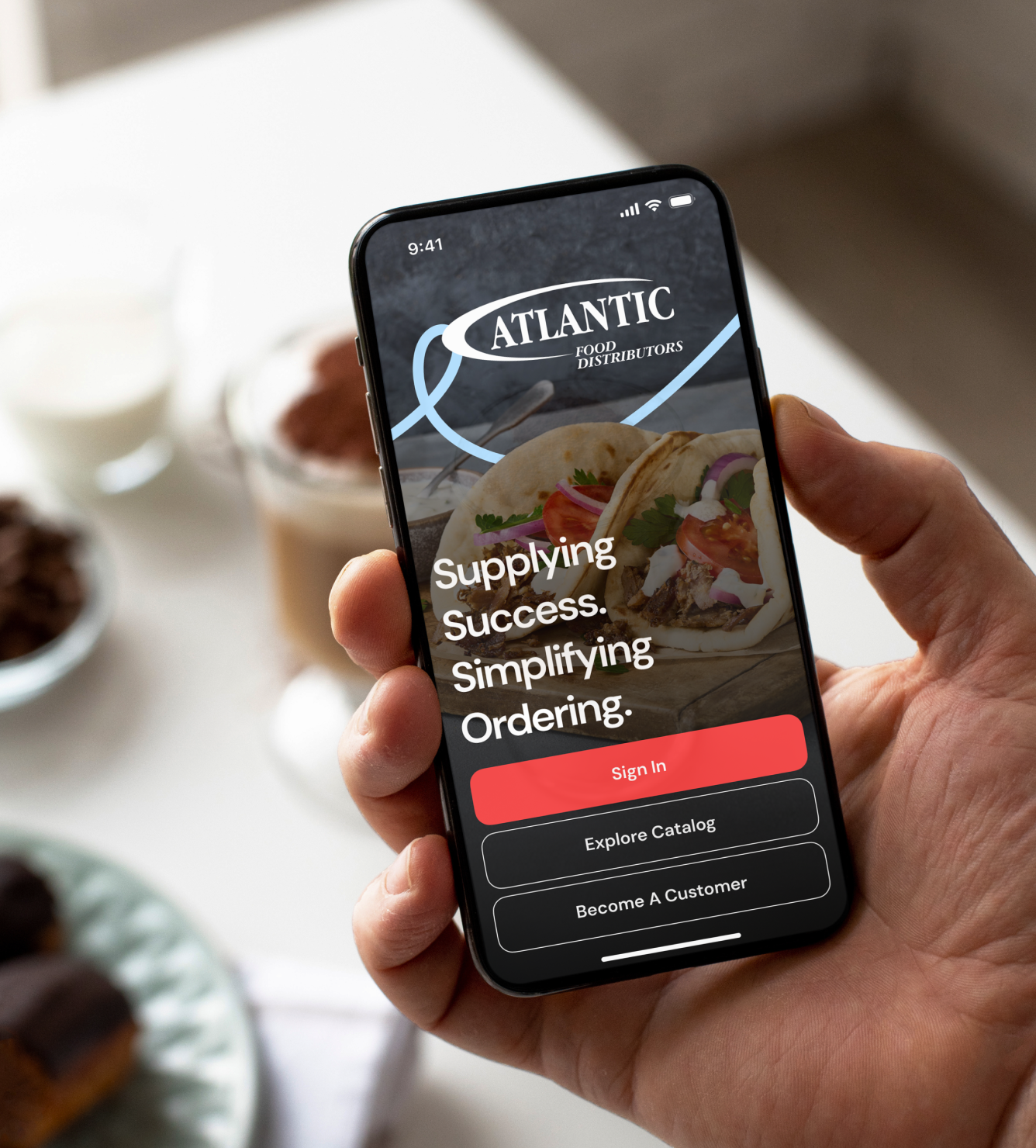 Atlantic Food Distributors app on a phone displaying "Supplying Success. Simplifying Ordering.