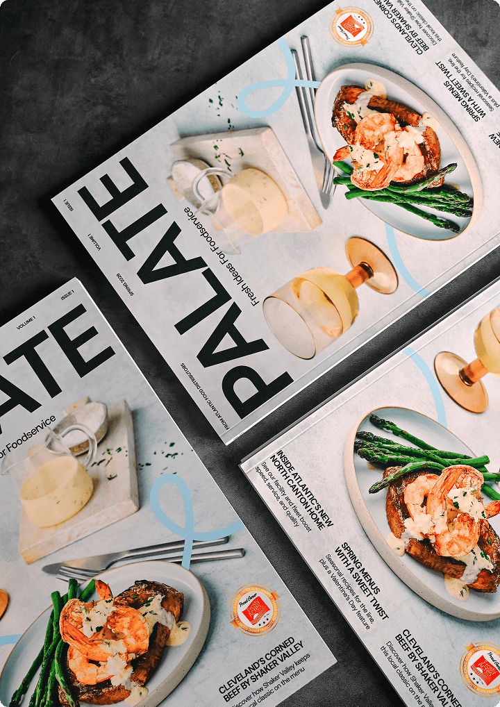 Magazines titled "Palate" featuring gourmet food photography, including shrimp and asparagus dishes, and a creamy dessert, arranged on a textured surface.