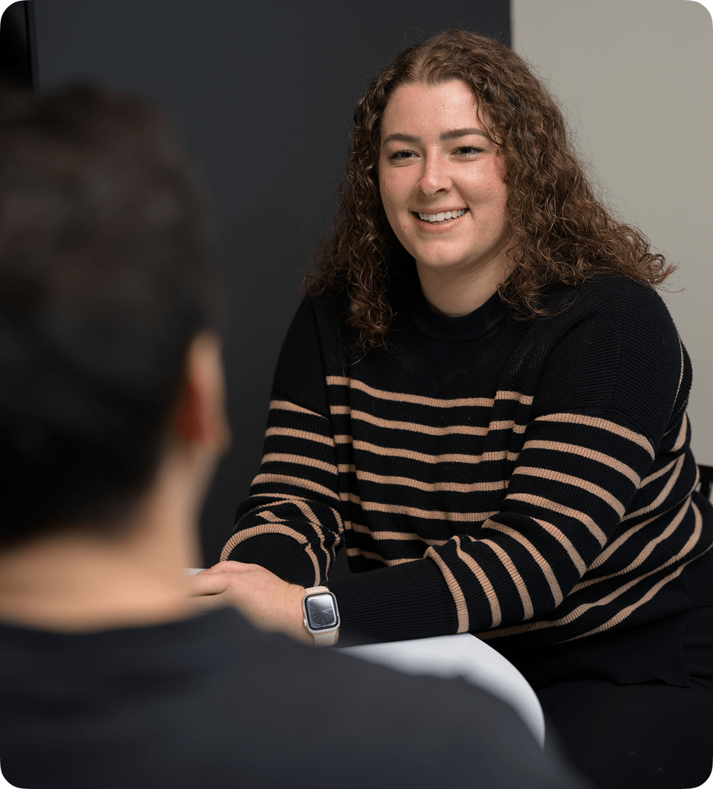 A woman smiling during a face-to-face business meeting in a modern office.